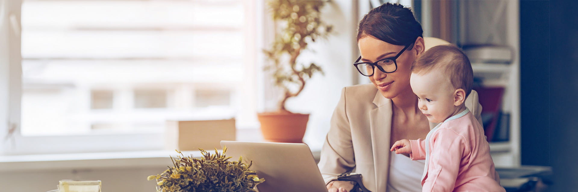 A working mother using her laptop whilst holding her baby