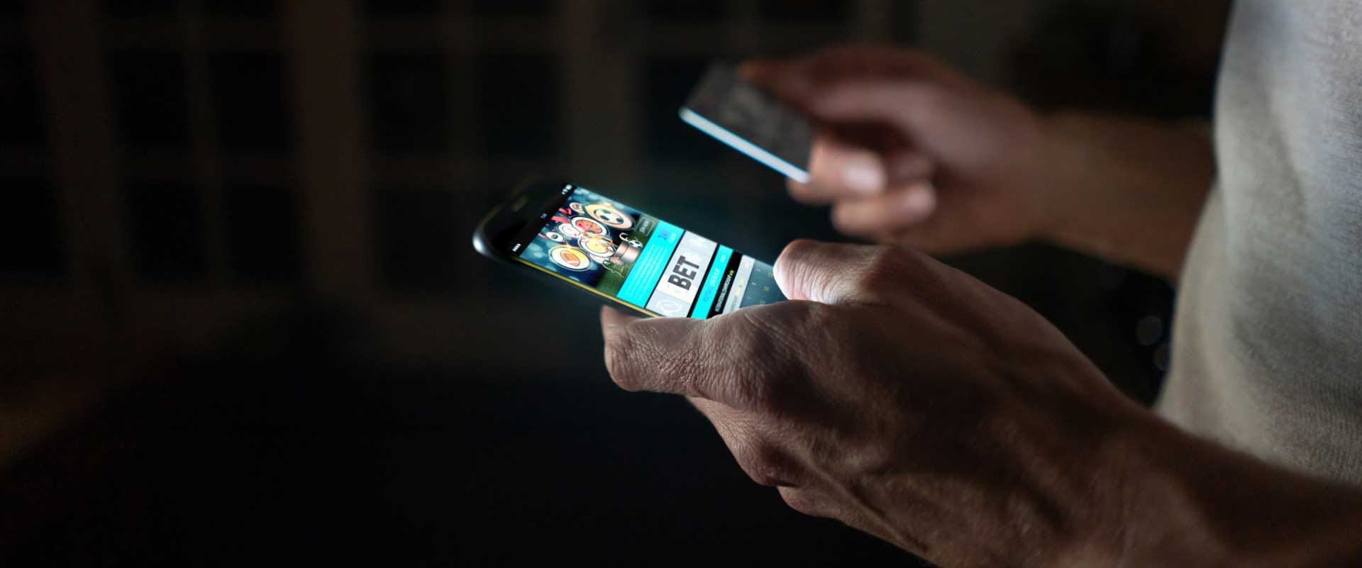 Someone using a mobile phone to add funds to their gambling account.