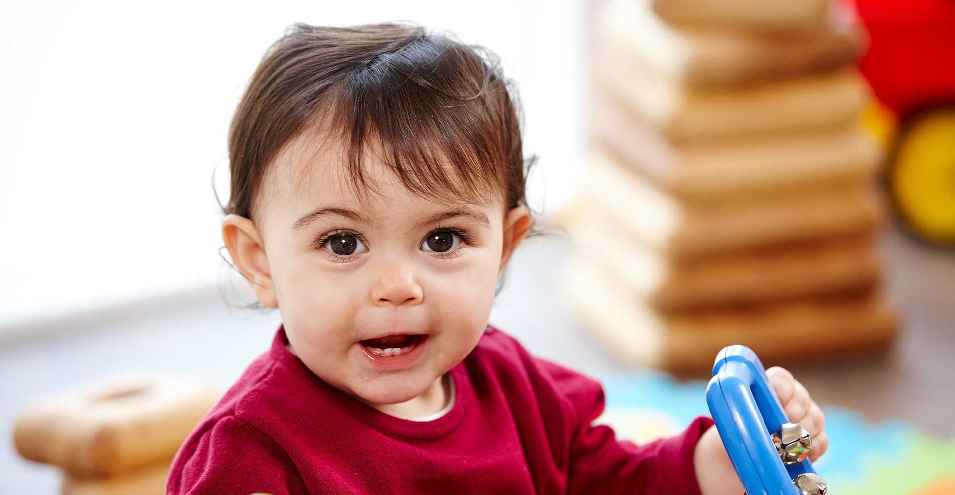 An infant is playing with a rattle-toy